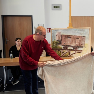 Rainer Schulz und Bürgermeister Dr. Hans-Peter Schick enthüllen im Mechernicher Ratssaal ein Bild, das an die Deportation der Juden erinnert.