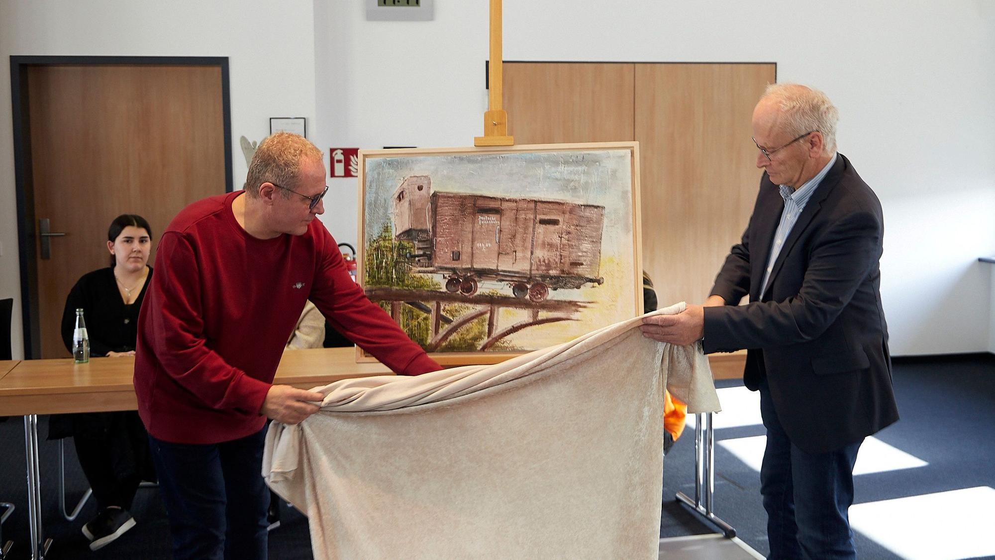 Rainer Schulz und Bürgermeister Dr. Hans-Peter Schick enthüllen im Mechernicher Ratssaal ein Bild, das an die Deportation der Juden erinnert.