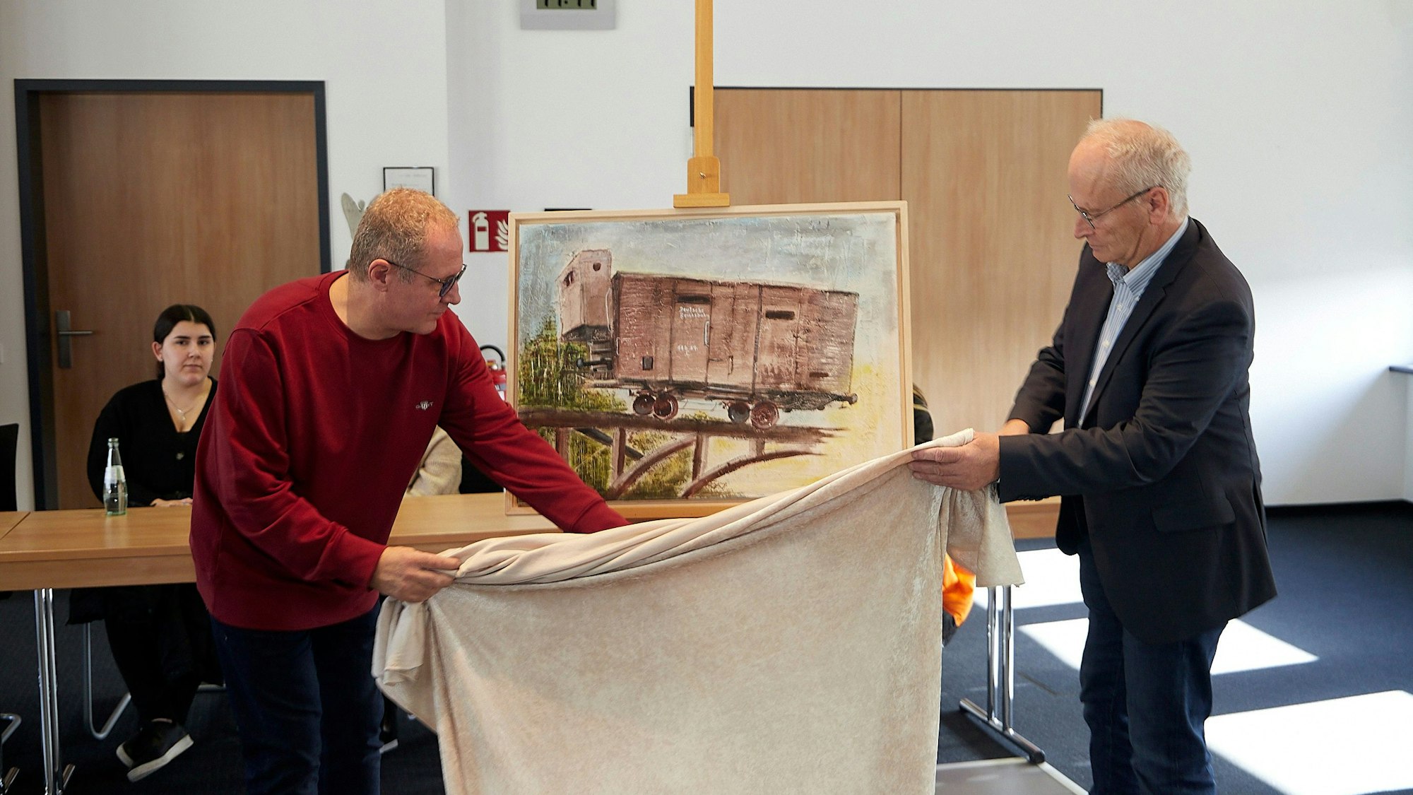 Rainer Schulz und Bürgermeister Dr. Hans-Peter Schick enthüllen im Mechernicher Ratssaal ein Bild, das an die Deportation der Juden erinnert.