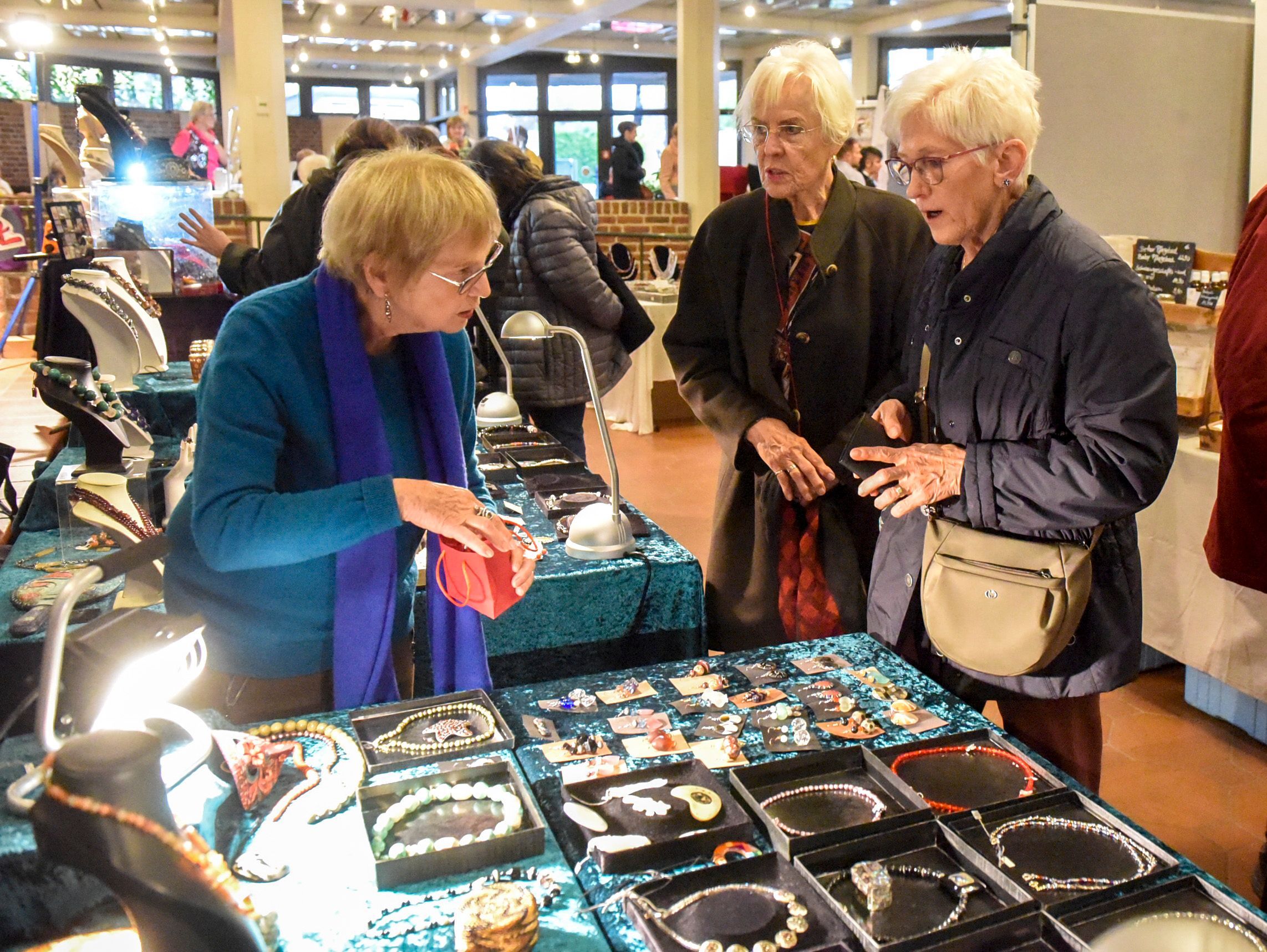 Besucherinnen des Handwerkermarktes sehen sich Schmuck an einem Stand an.