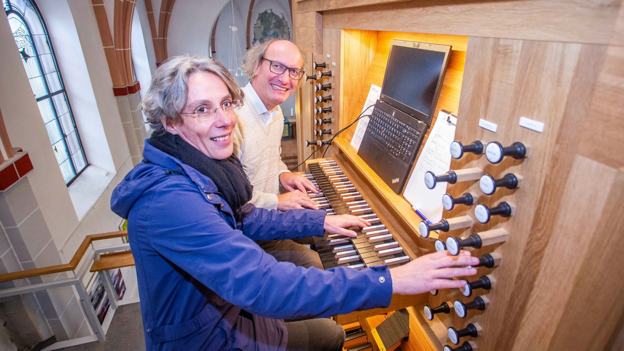Zwei Personen spielen an einer Kirchenorgel