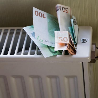 Euro-Banknoten stecken in einem Heizkörper