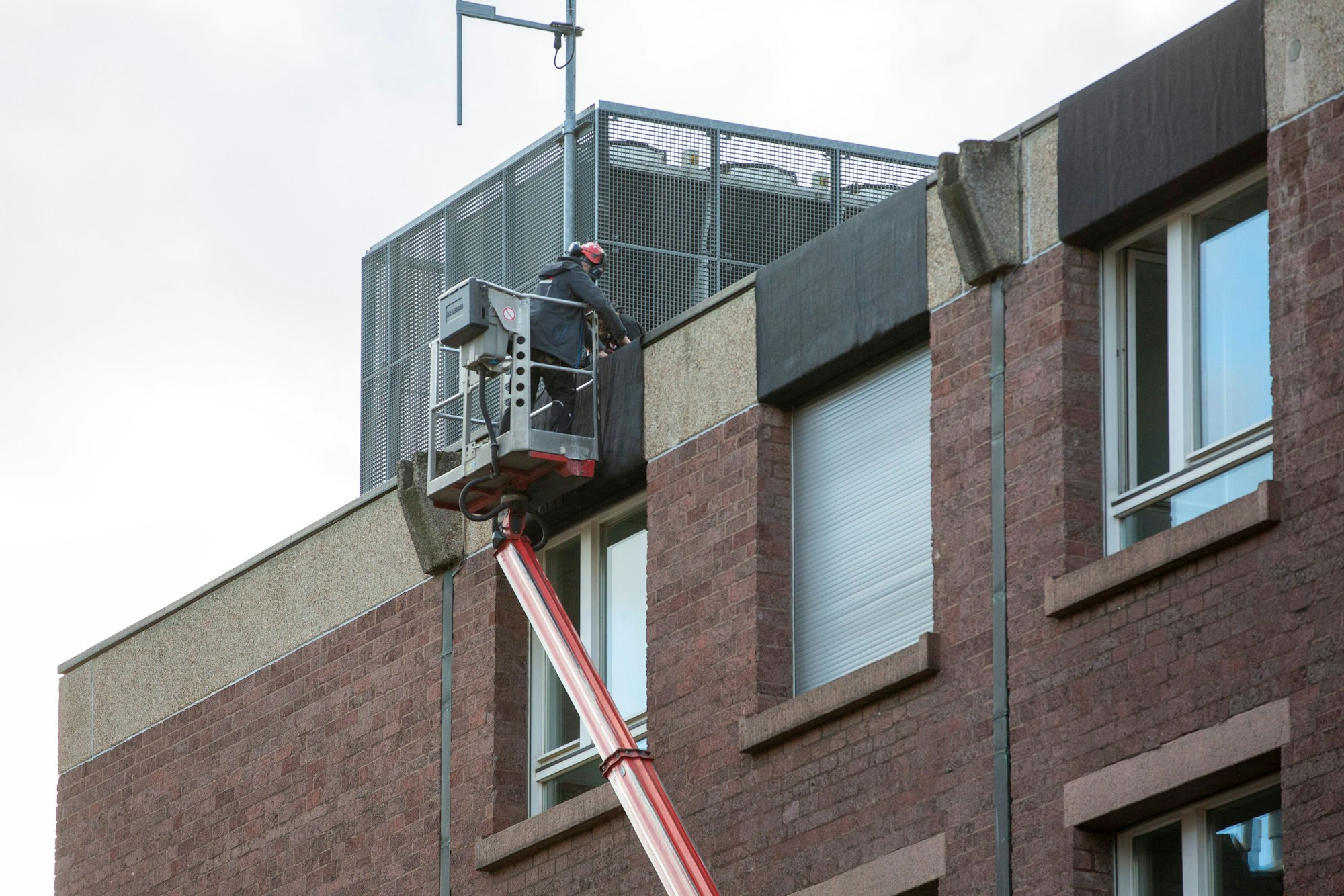 Ein Arbeiter auf einem Hubsteiger bringt Planen zum Schutz vor herabfallenden Bauteilen am Historischen Rathaus in Köln an.
