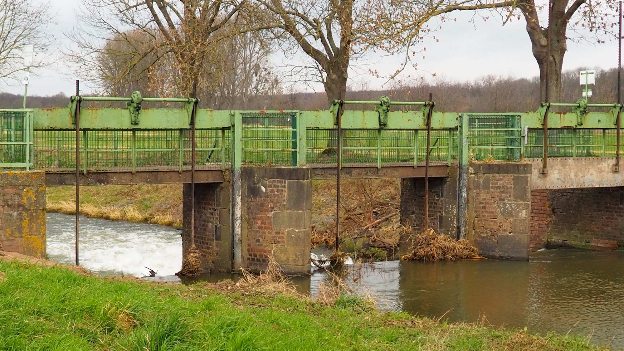 Ein Fluss mit schnurgeraden Ufern fließt durch ein Wehr.