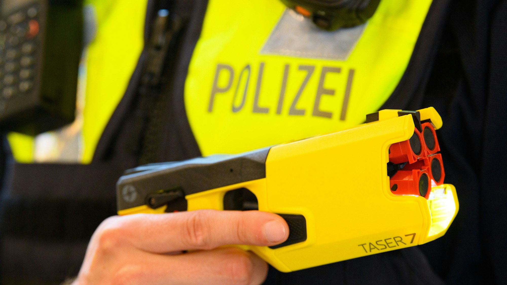 Ein Polizeibeamter hält im Rahmen der Pressekonferenz des Polizeipräsidenten einen Taser 7 in der Hand.