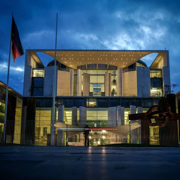 Das Bundeskanzleramt wird am Abend angestrahlt, vor ihm wehen eine Deutschland- und eine Europaflagge.