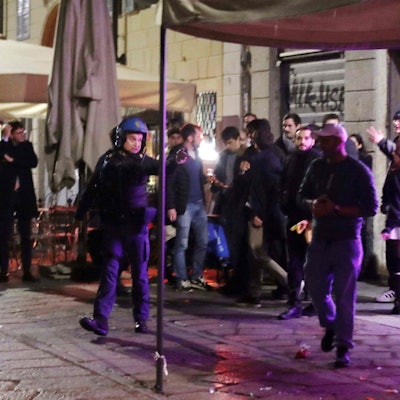 Ein italienischer Polizist ist nach den Krawallen in Mailand um Ordnung bemüht.