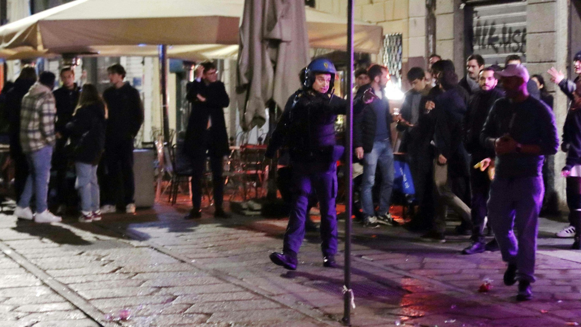 Ein italienischer Polizist ist nach den Krawallen in Mailand um Ordnung bemüht.