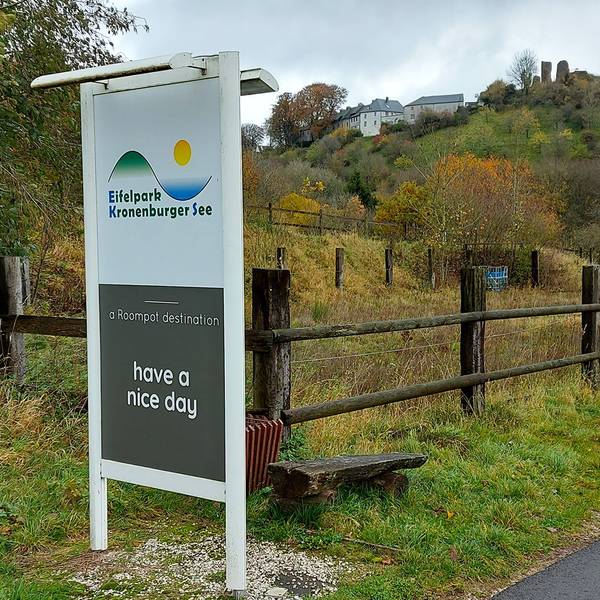 Ein Schild an der Einfahrt zum Ferienpark in Kronenburg, im Hintergrund ist das Dorf zu sehen.