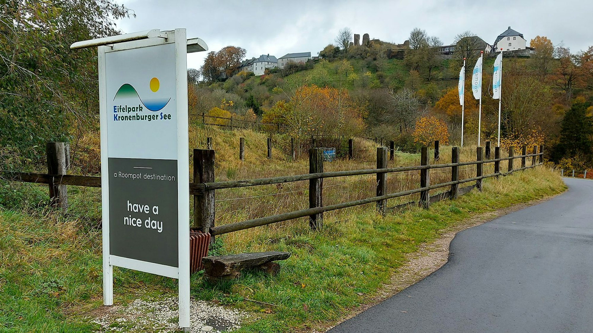 Ein Schild an der Einfahrt zum Ferienpark in Kronenburg, im Hintergrund ist das Dorf zu sehen.