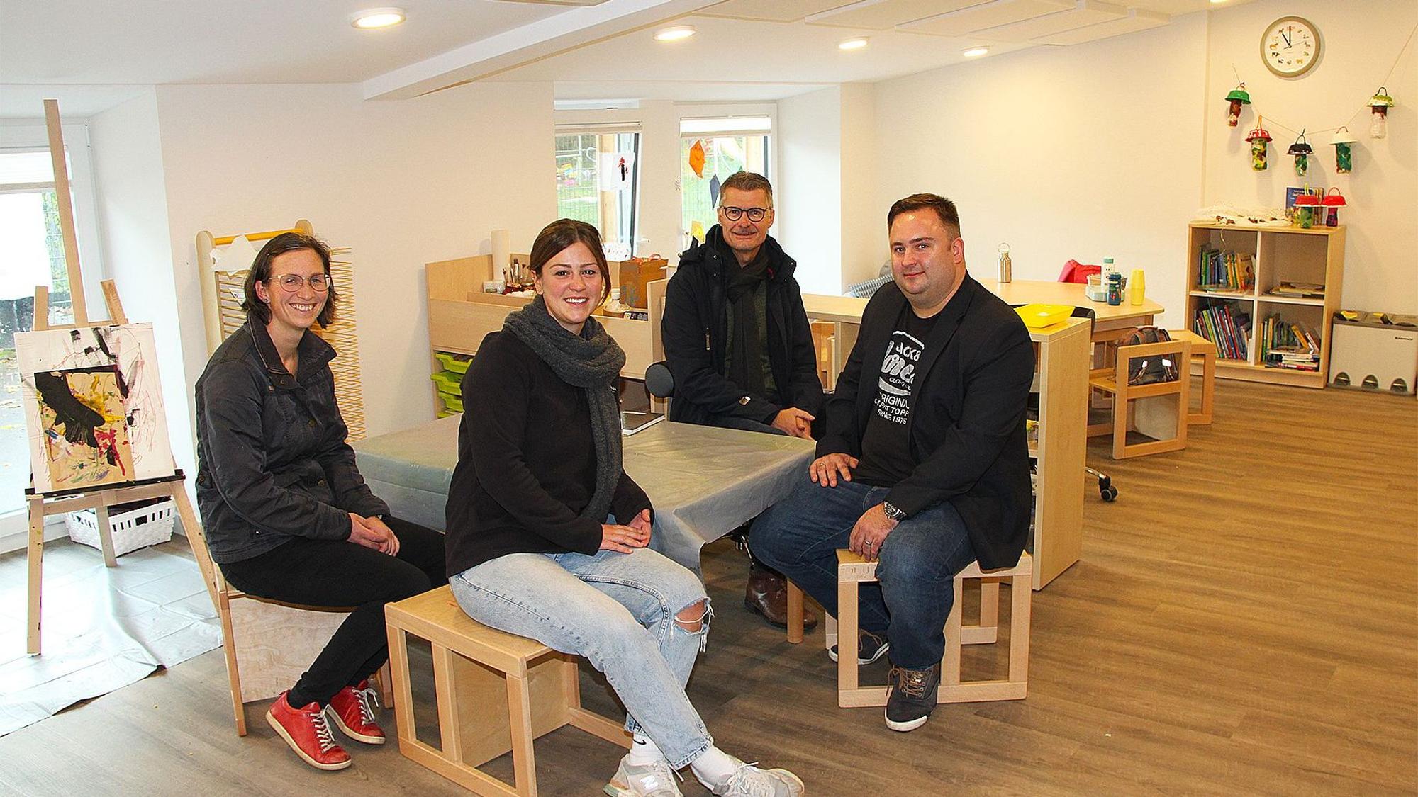 Die vier Genannten sitzen an einem Tisch im gemütlichen Gruppenraum des Kindergartens.