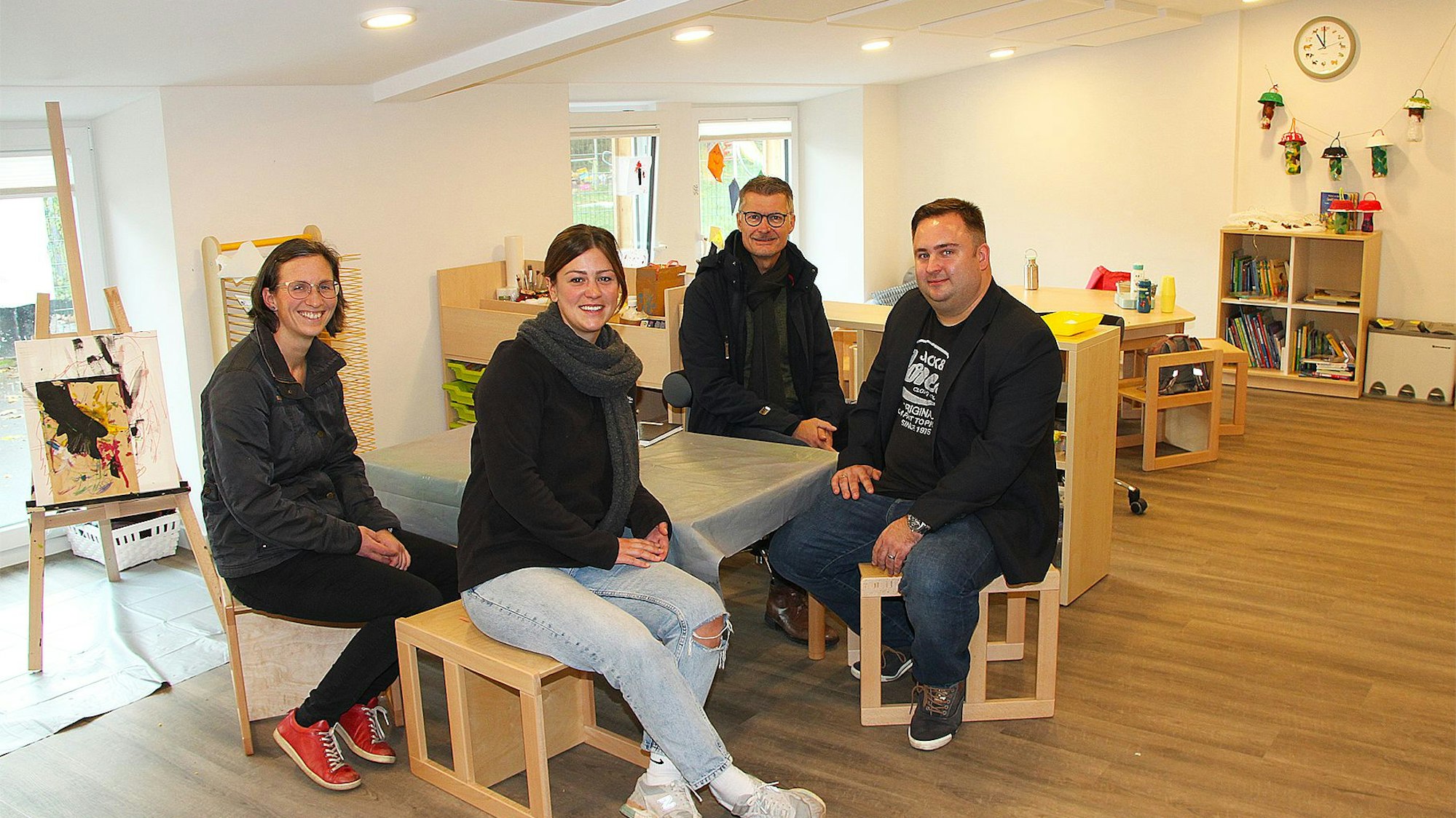 Die vier Genannten sitzen an einem Tisch im gemütlichen Gruppenraum des Kindergartens.