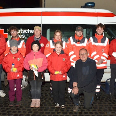 Gruppenbild mit den Mitgliedern des DRK-Ortsverbands Mechernich vor einem Rotkreuz-Kleinbus. Einige tragen Einsatzkleidung mit Reflektor-Streifen.