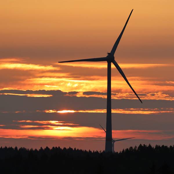 Das Bild zeigt ein Windrad in einem Wald auf dem Gebiet der Gemeinde Dahlem in der Abenddämmerung.