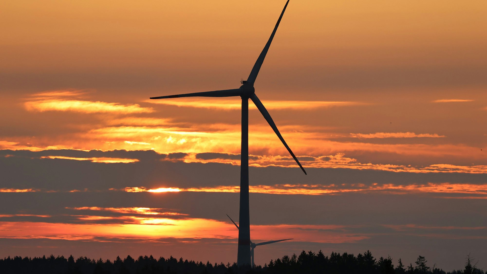 Das Bild zeigt ein Windrad im Sonnenaufgang.