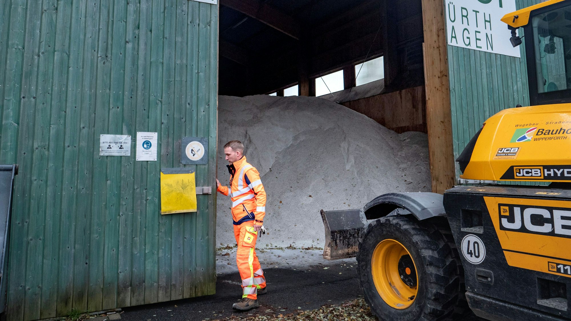 Ein Mitarbeiter des Bauhofs schiebt eine Hallentüre auf. Dahinter sind Berge von Streusalz zu sehen.