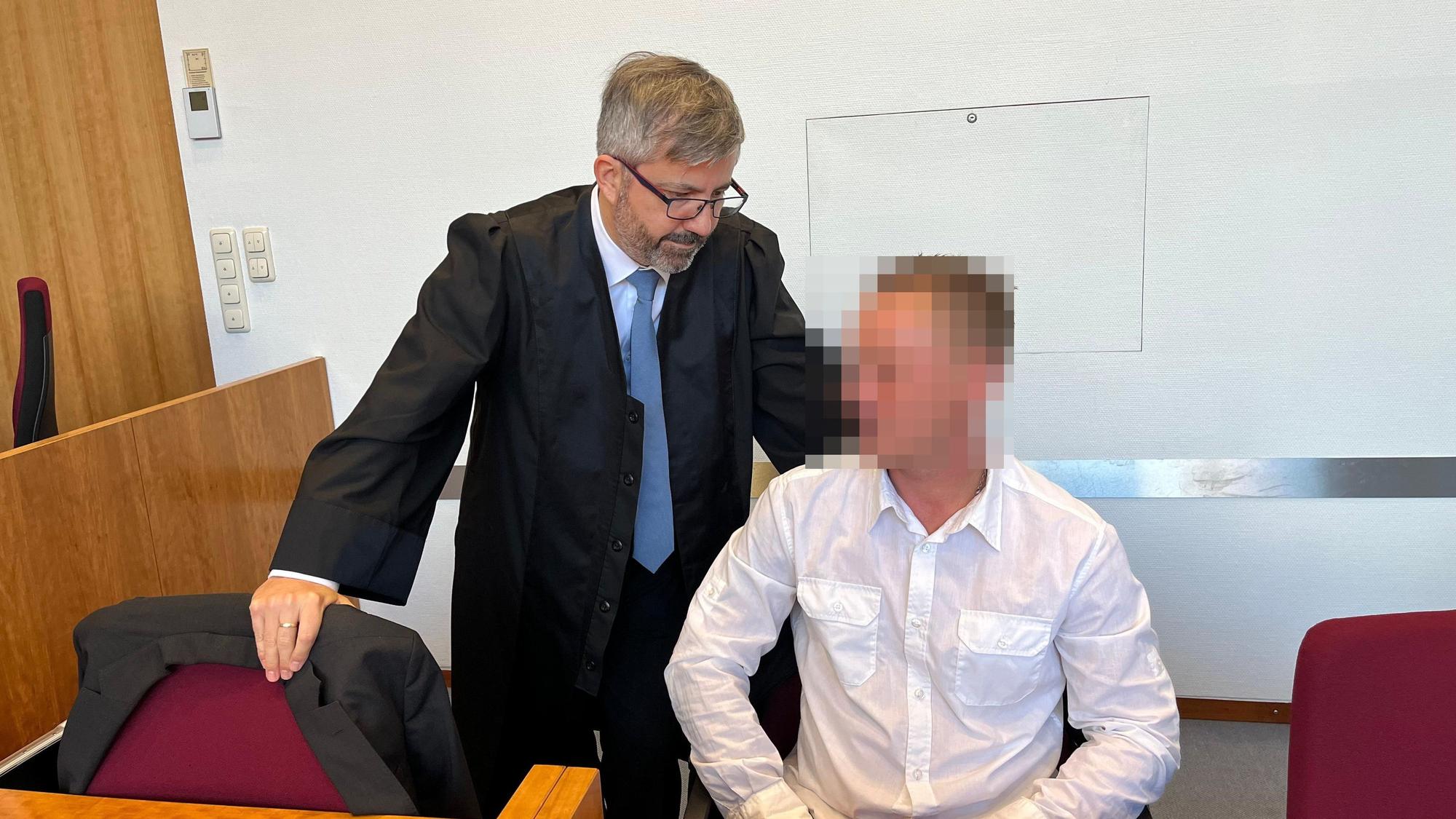 Ein Mann sitzt auf der Anklagebank. Neben ihm steht sein Anwalt.