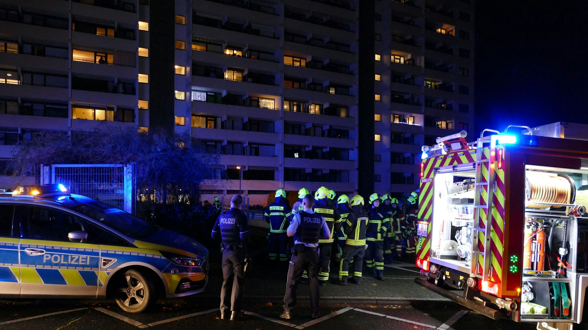 Feuerwehr und Polizei stehen vor einem Hochhaus.