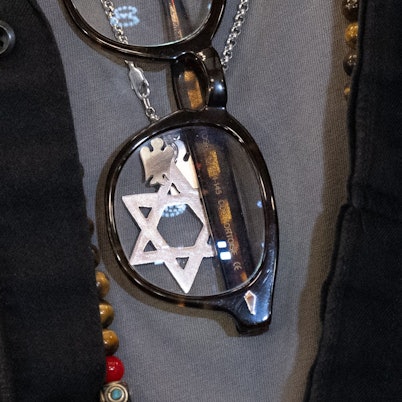 Im Ausschnitt eines T-Shirts steckt eine Brille, dahinter sieht man einen silbernen Davidstern an einer Kette.