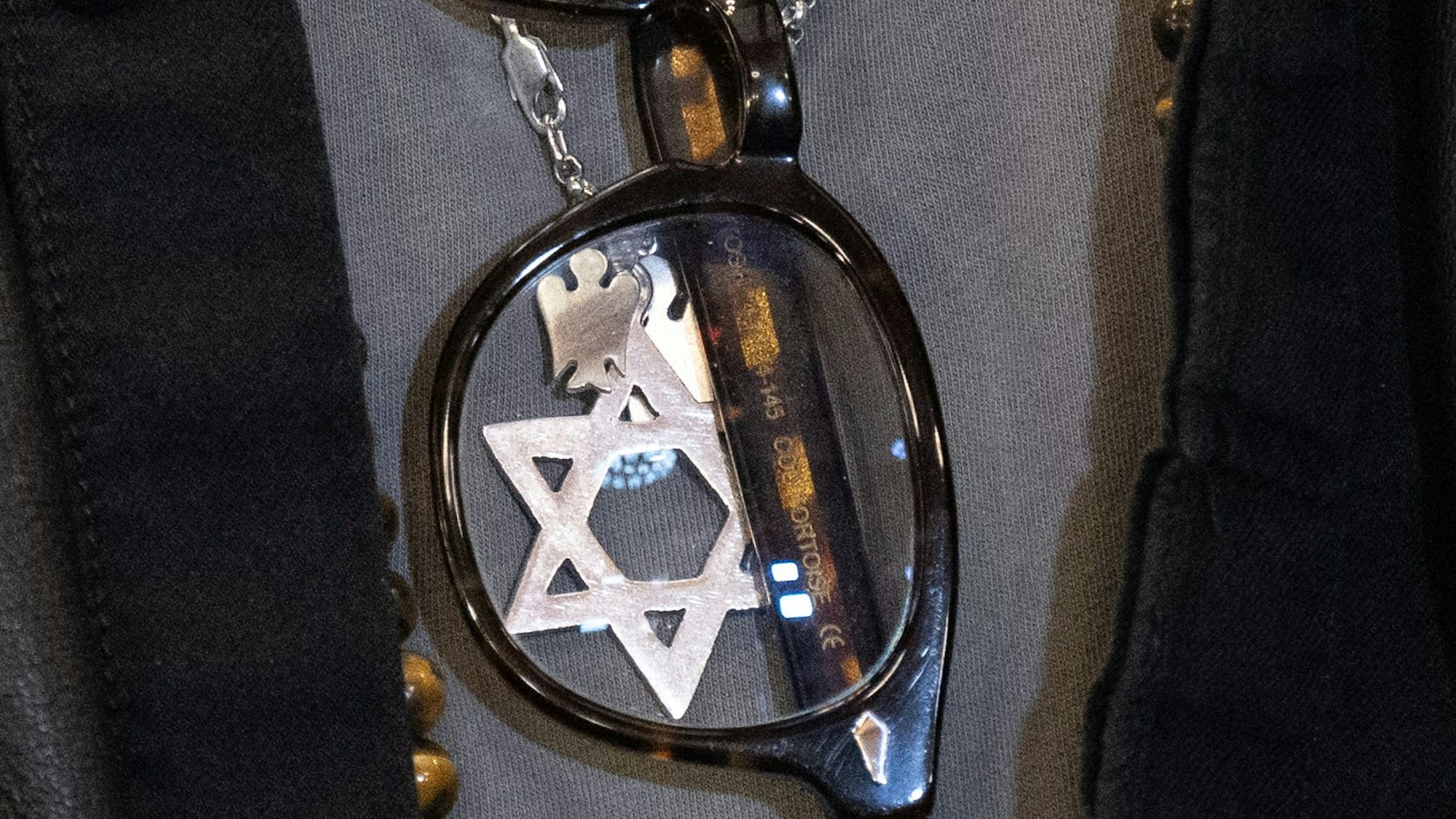 Im Ausschnitt eines T-Shirts steckt eine Brille, dahinter sieht man einen silbernen Davidstern an einer Kette.