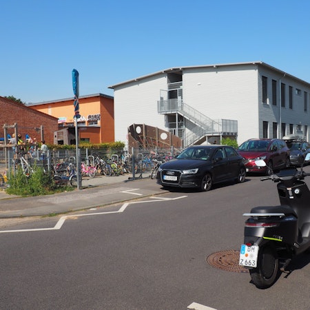 Im Hintergrund ist links ein Schulgebäude zu sehen, rechts ein Modulbau.