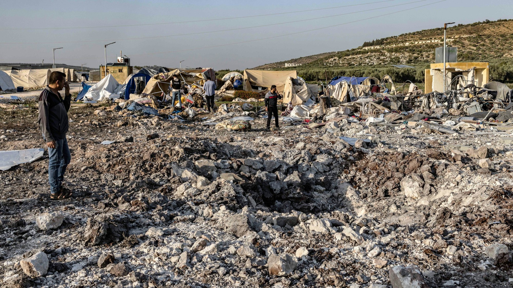 Syrien, Al-Hamamah: Menschen begutachten die Zerstörung, die ein russischer Luftangriff auf ein Vertriebenenlager verursacht hat.