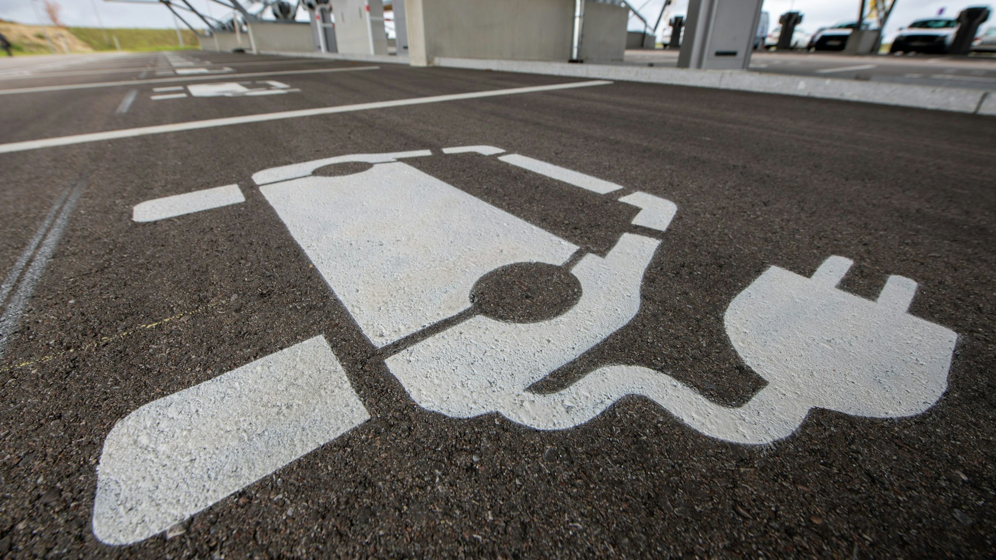 Vor einem Ladepunkt in einem Ladepark ist ein Symbol für ein E-Auto aufgemalt