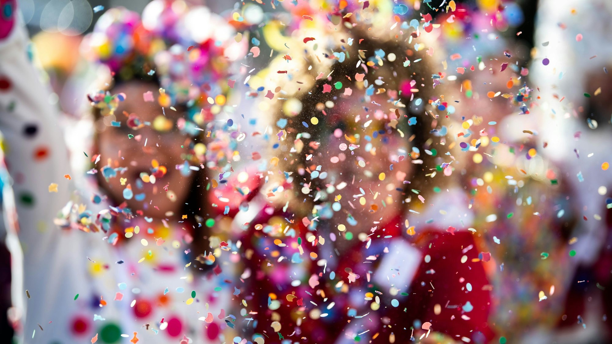 Das Bild zeigt Konfetti vor zwei weiblichen Karnevalsjecken.