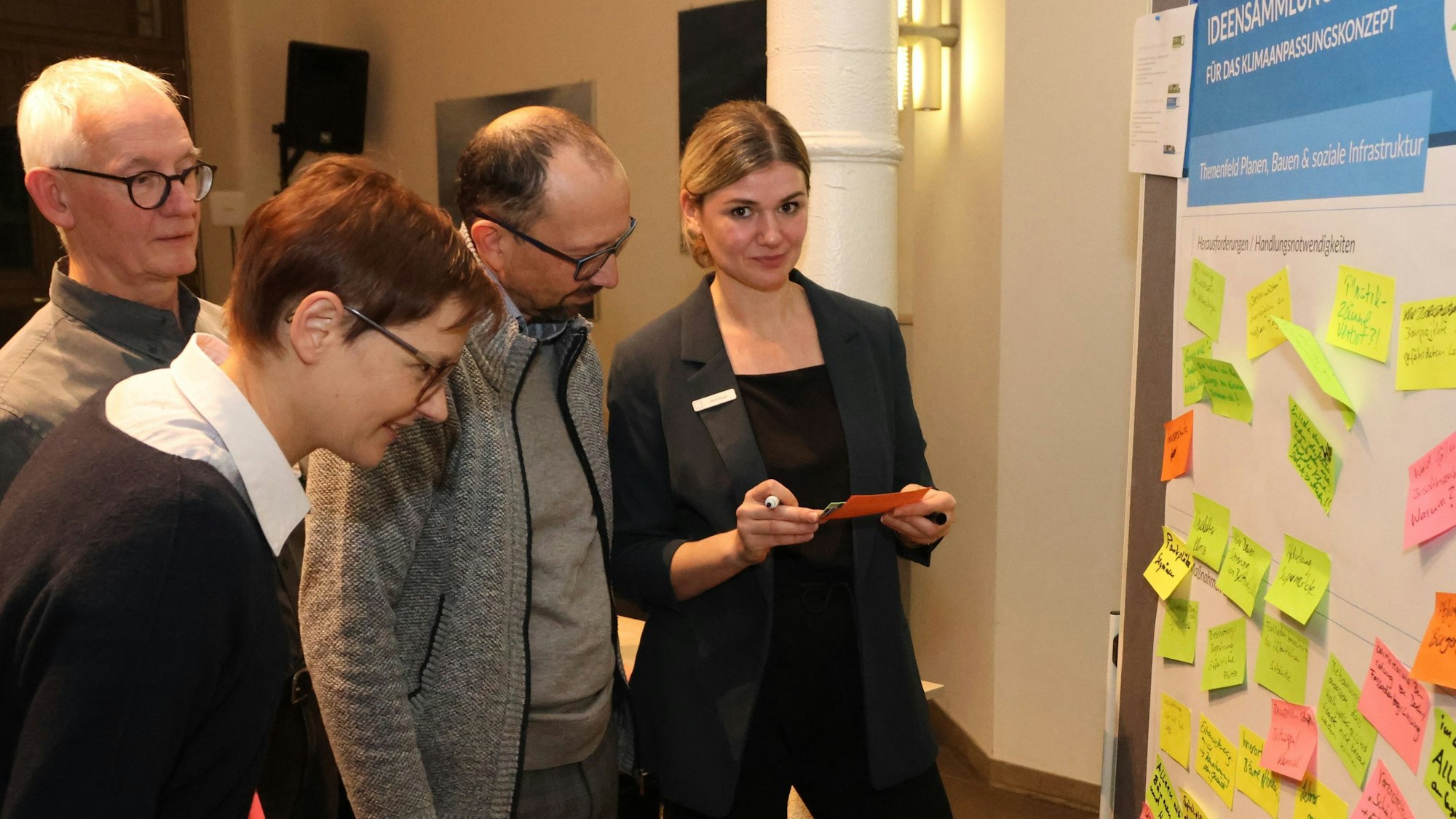 Maren Bogon (rechts) steht mit Teilnehmern des Bürgerworkshops in Engelskirchen vor einer Magnettafel mit vielen farblichen Post-It-Zetteln.