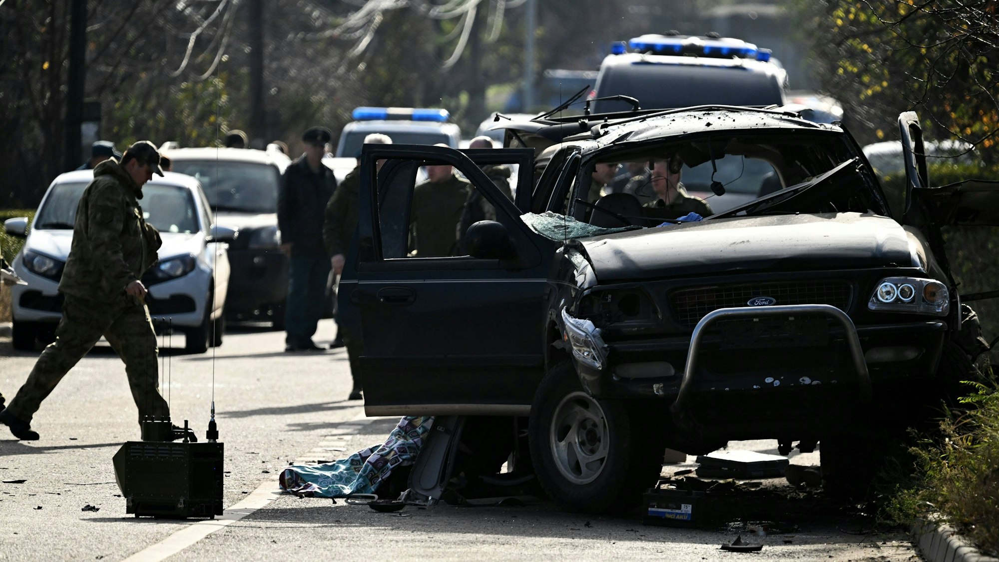 Einsatzkräfte stehen hinter einem ramponierten LKW.