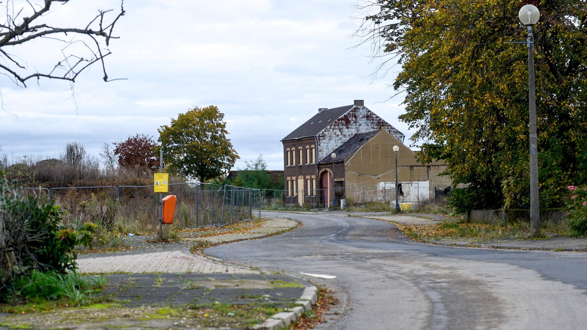 Das Bild zeigt ein Haus im alten Manheim, daneben stehen Bauzäune. Auf den Bürgersteigen wachsen Pflanzen.