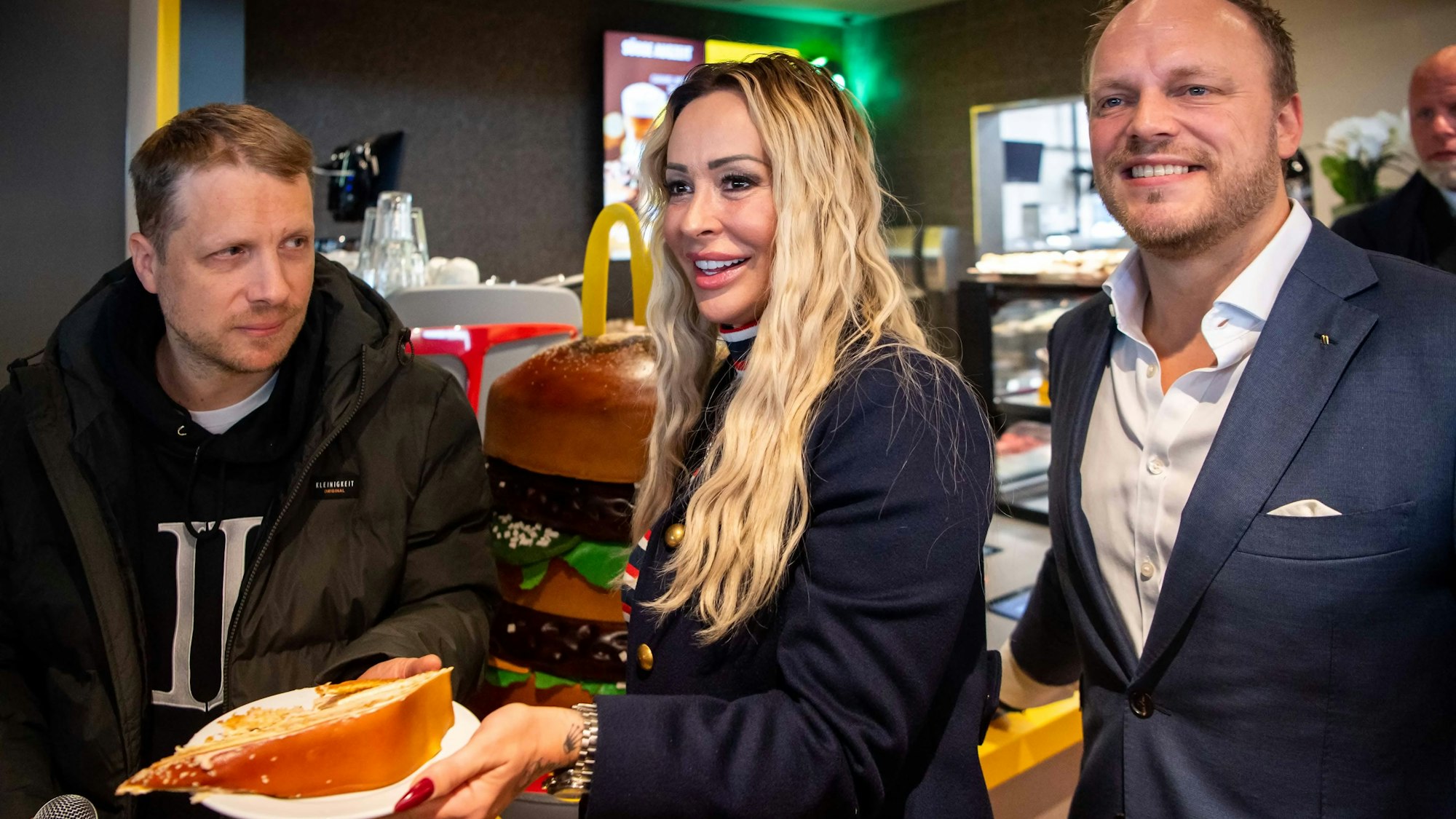 Das Bild zeigt unter anderem Oliver Pocher und Cora Schumacher, wie sie Kuchen herausgeben.