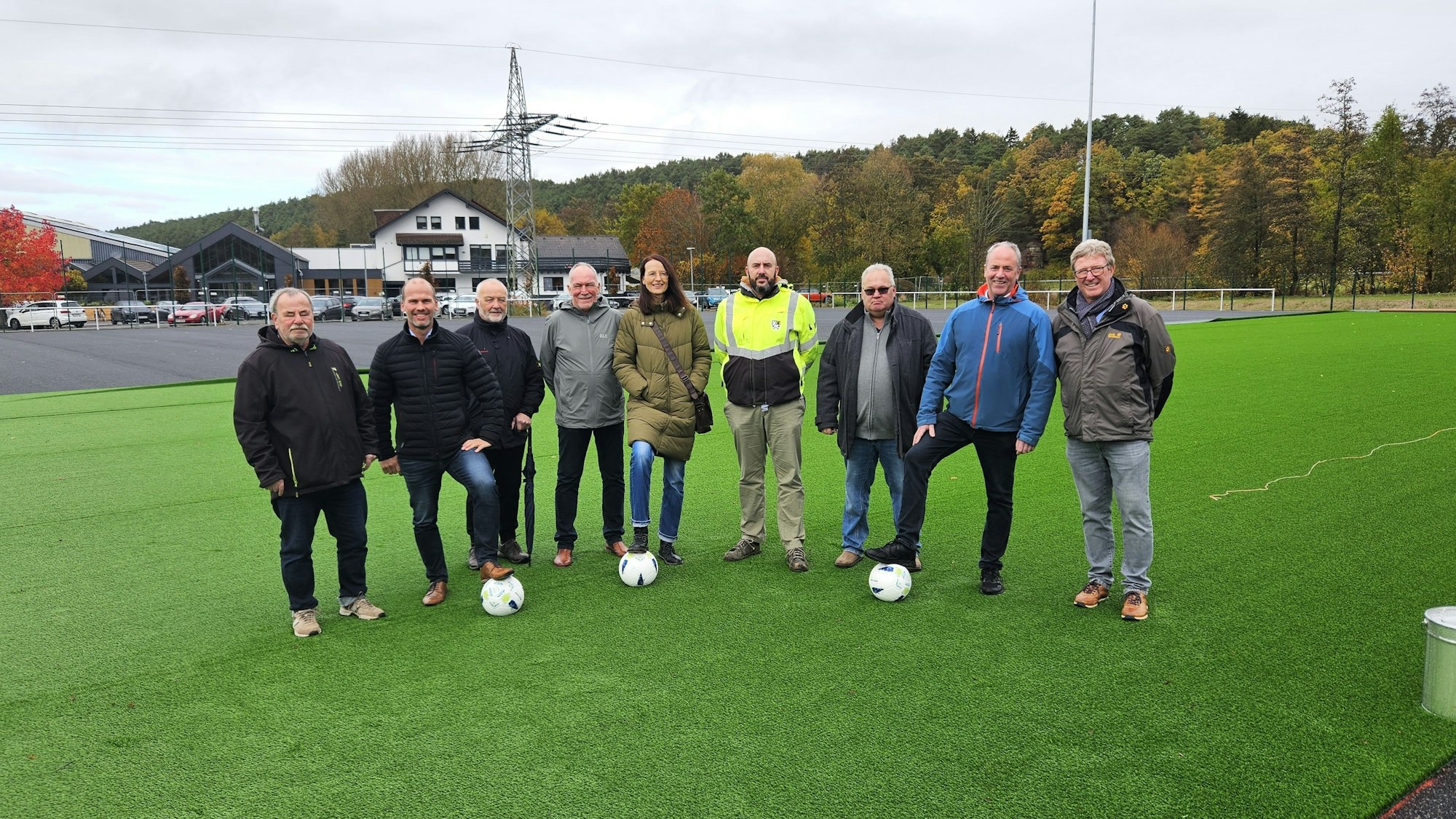Manfred Poth und Hermann-Josef Esser stehen mit Vertretern der Verwaltung und des Kaller SC auf der Kunstrasenfläche.