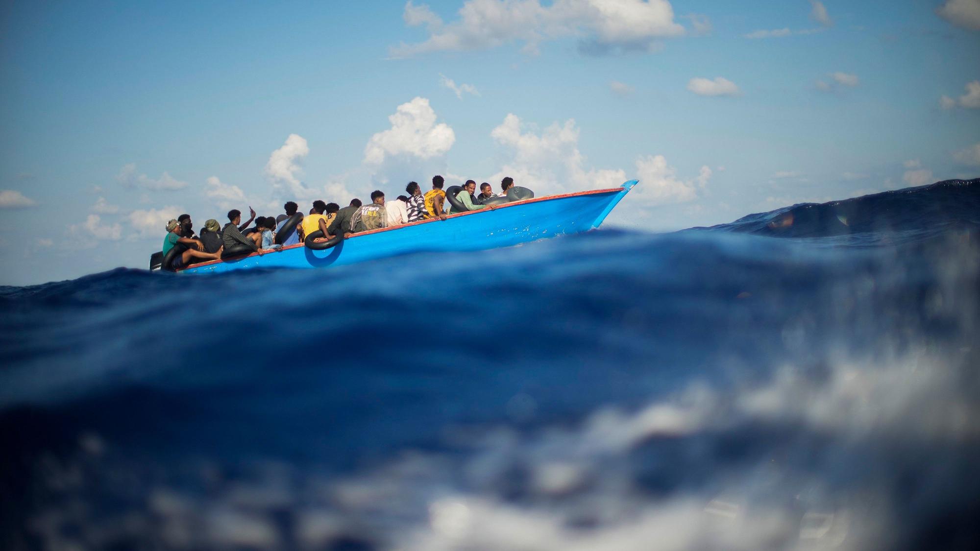 Flüchtende sitzen in einem Holzboot auf dem Mittelmeer kurz vor der Insel Lampedusa. Seenotretter kritisieren die geplanten Gesetzesänderungen zur Migration. (Symbolbild)