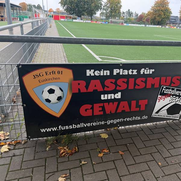 Das Bild zeigt ein Schild mit der Aufschrift „Kein Platz für Rassismus und Gewalt“ auf dem Sportplatz der JSG Erft in Kuchenheim.
