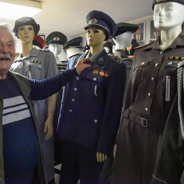 Das Foto zeigt Armin Schmitt vor Uniformen aus der ehemaligen DDR.