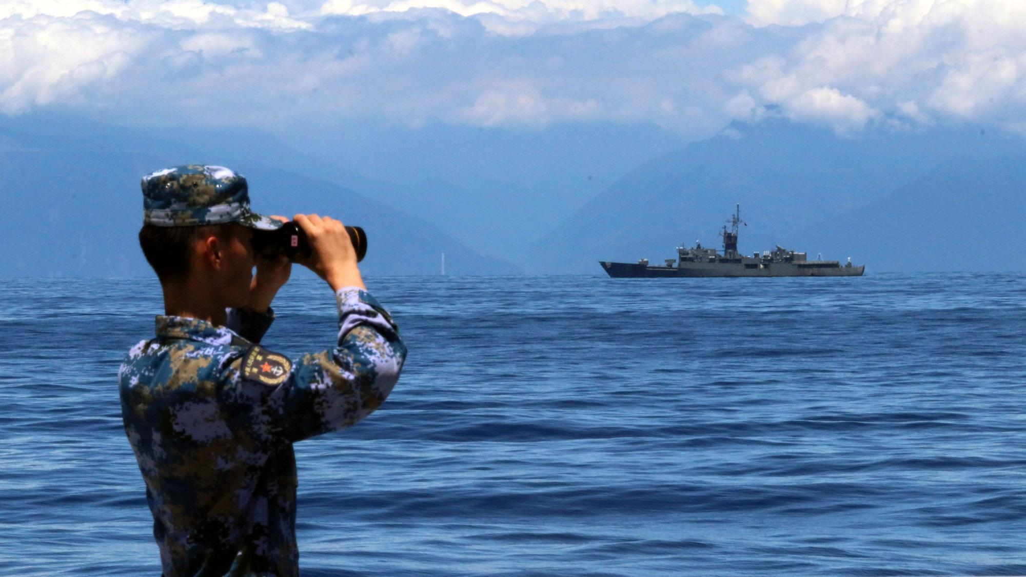 Das von der chinesischen Nachrichtenagentur Xinhua veröffentlichte Foto zeigt eine Mitglied der chinesischen Volksbefreiungsarmee, der während einer Militärübung auf See durch ein Fernglas guckt während im Hintergrund Taiwans Fregatte Lan Yang zu sehen ist.