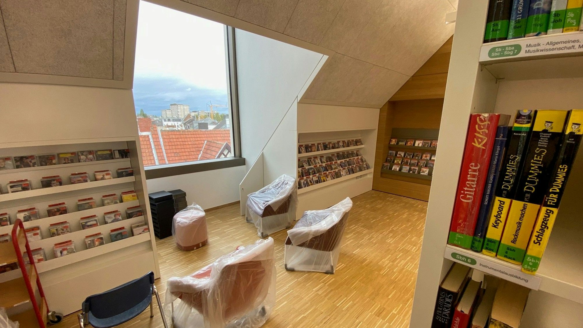 Zu sehen sind Sessel, Bücherregale und ein großes Fenster.