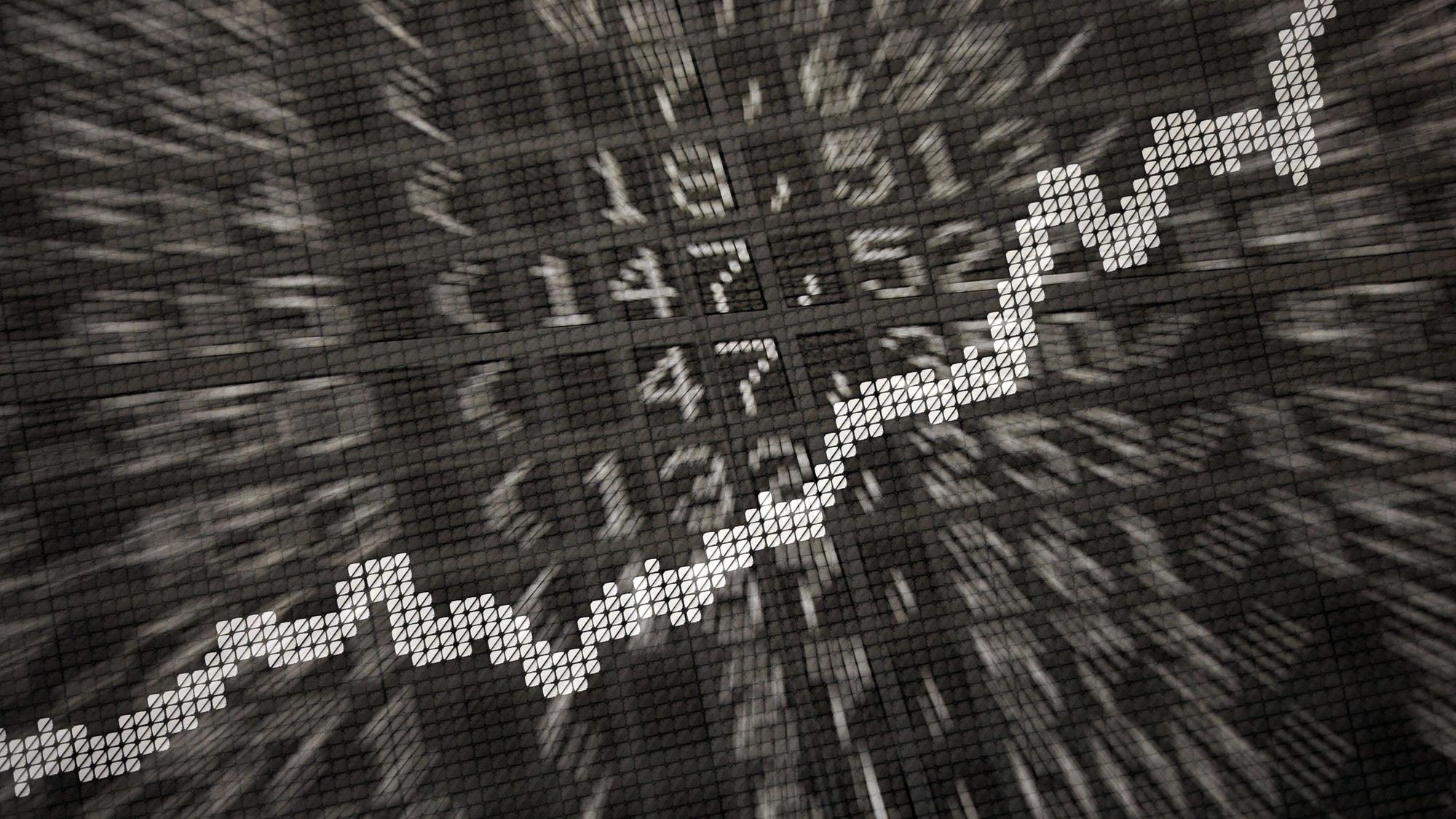 Die große Anzeige in der Börse zeigt die Dax-Kurve und verschiedene Börsenkurse.