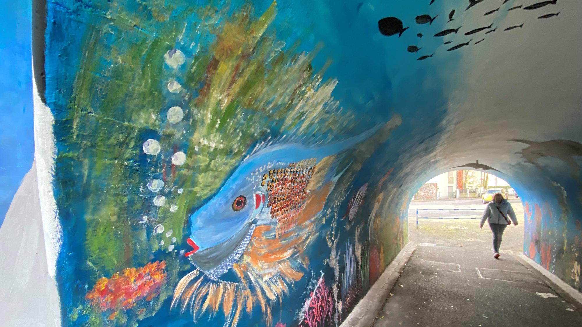 Zu sehen ist die mit einem bunten Fisch bemalte Tunnelwand.