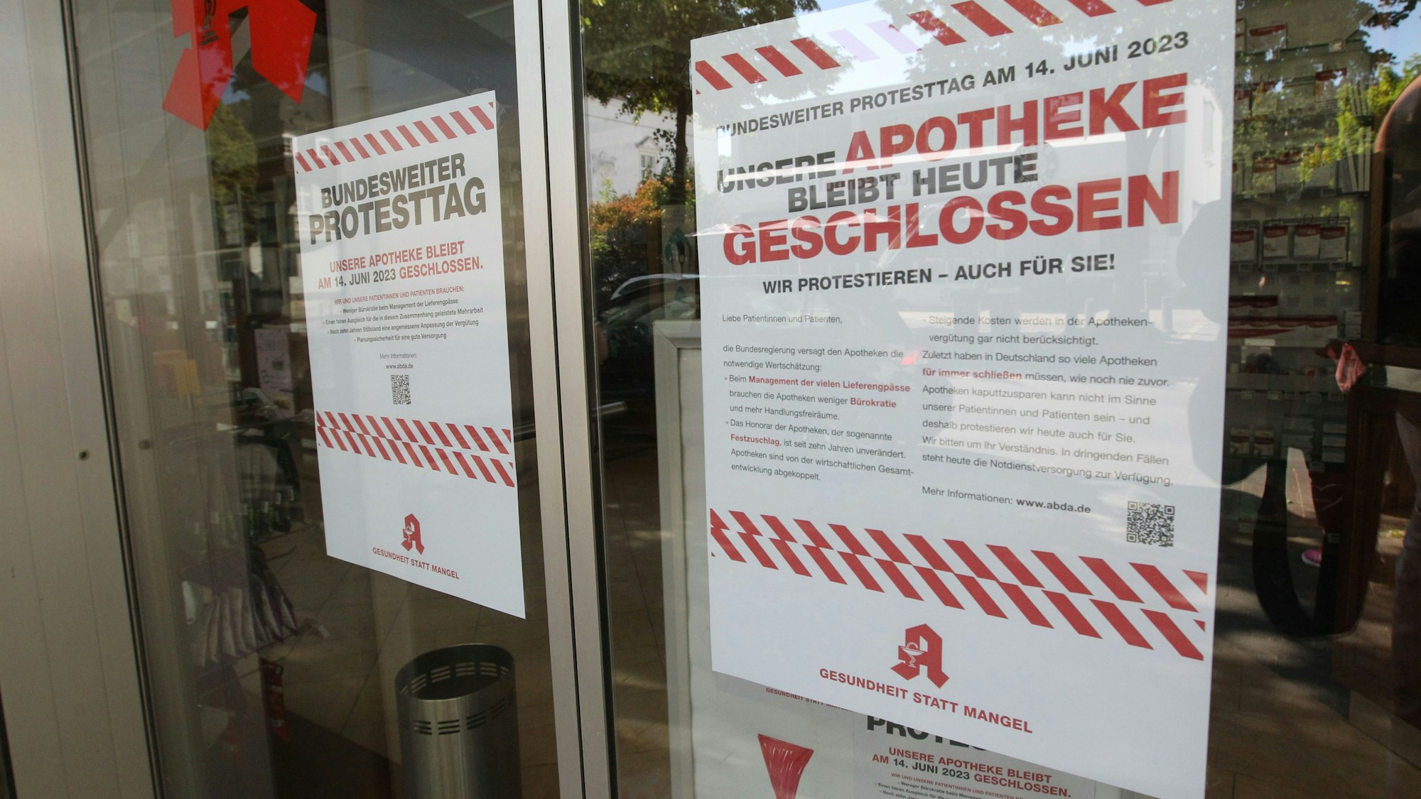 Ein Protestschild hängt in der Scheibe einer Apotheke.