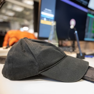 Eine Baseballmütze liegt in einem Coworking-Space auf dem Tisch eines Programmierers.