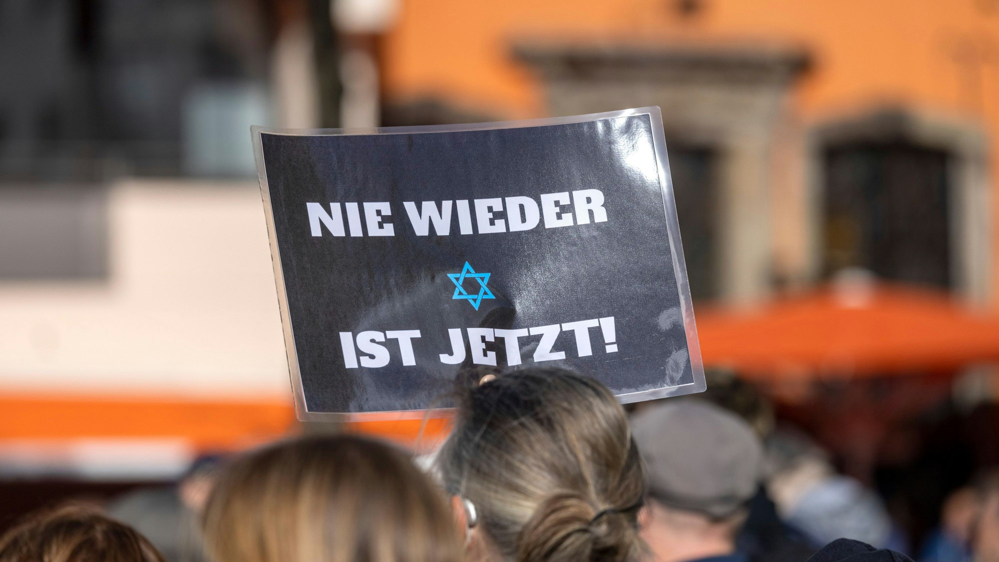 Ein Teilnehmer der Kundgebung «Aufstehen gegen Israelhass und Antisemitismus» hält ein Plakat mit der Aufschrift: ·Nie wieder ist jetzt· in die Höhe.