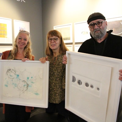 Zwei Frauen und ein Mann mit zwei Bildern in Bilderrahmen