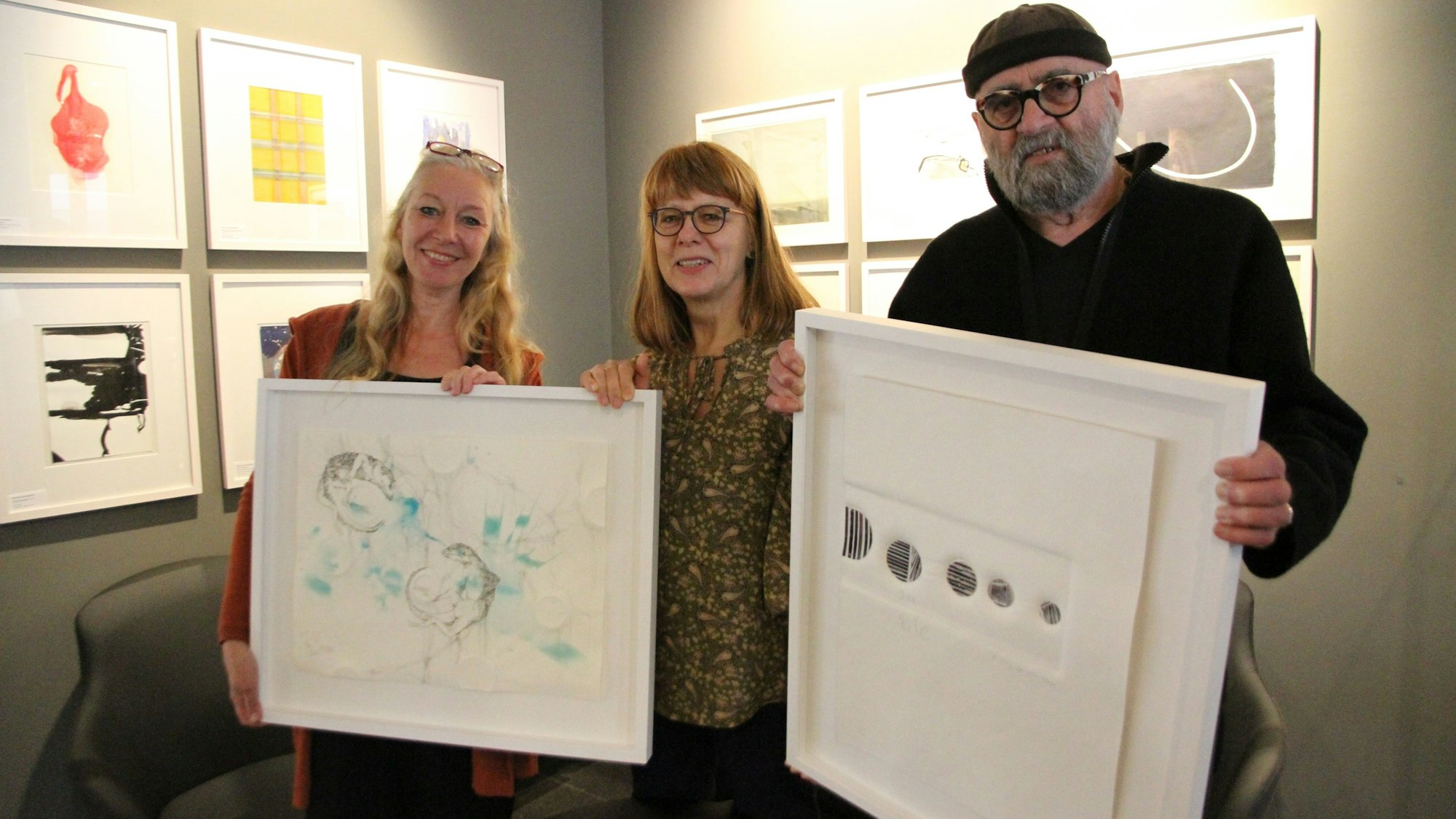 Zwei Frauen und ein Mann mit zwei Bildern in Bilderrahmen