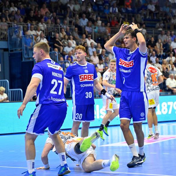 Drei VfL-Spieler stehen auf einem Handballfeld.