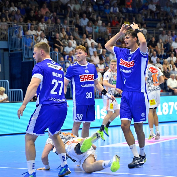 Drei VfL-Spieler stehen auf einem Handballfeld.
