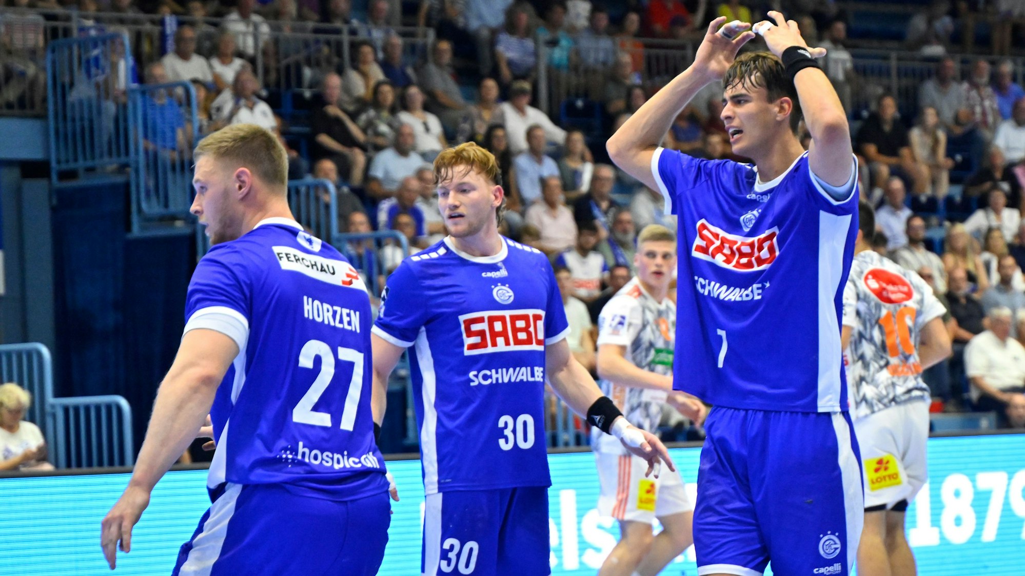 Drei VfL-Spieler stehen auf einem Handballfeld.
