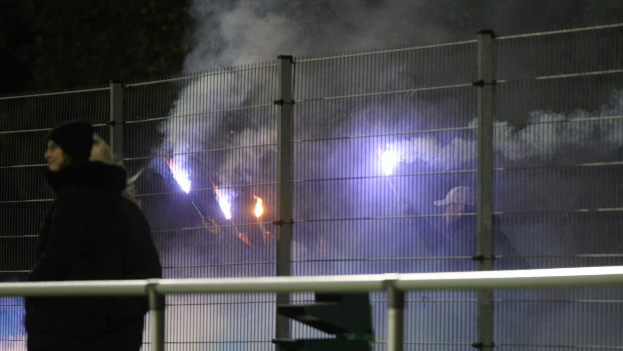 Fans der Sportfreunde D-H-O stehen hinter dem Zaun und zündeten Bengalos an.
