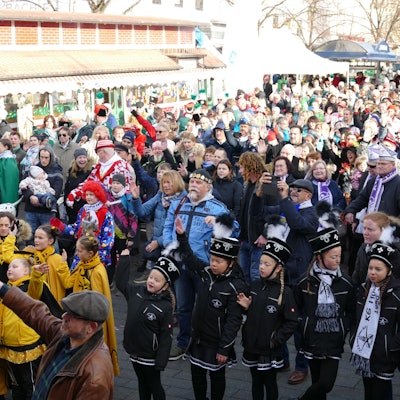 Kinder und Erwachsene stehen in einer großen Menge auf dem Siegburger Markt. Sie tragen Uniformen ihrer Karnevalsgesellschaften in vielen Farben.
